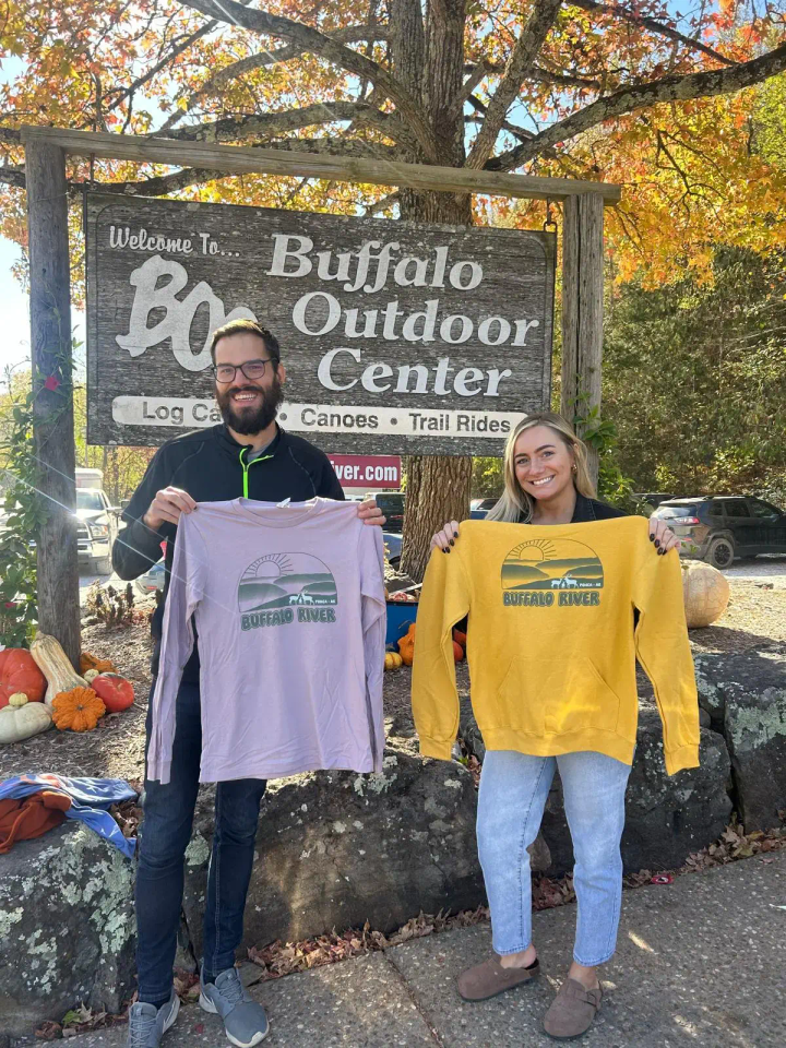 John from Splor with Buffalo Outdoor Center staff, smiling while holding their custom sweatshirts